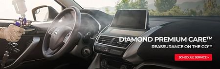 A Mitsubishi technician spraying Diamond Premium Care car disinfectant and deodorizer into the interior of a vehicle